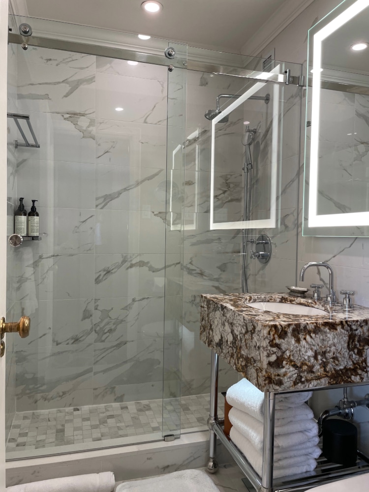 glass doored shower and marble vanity in a luxurious hotel master bathroom