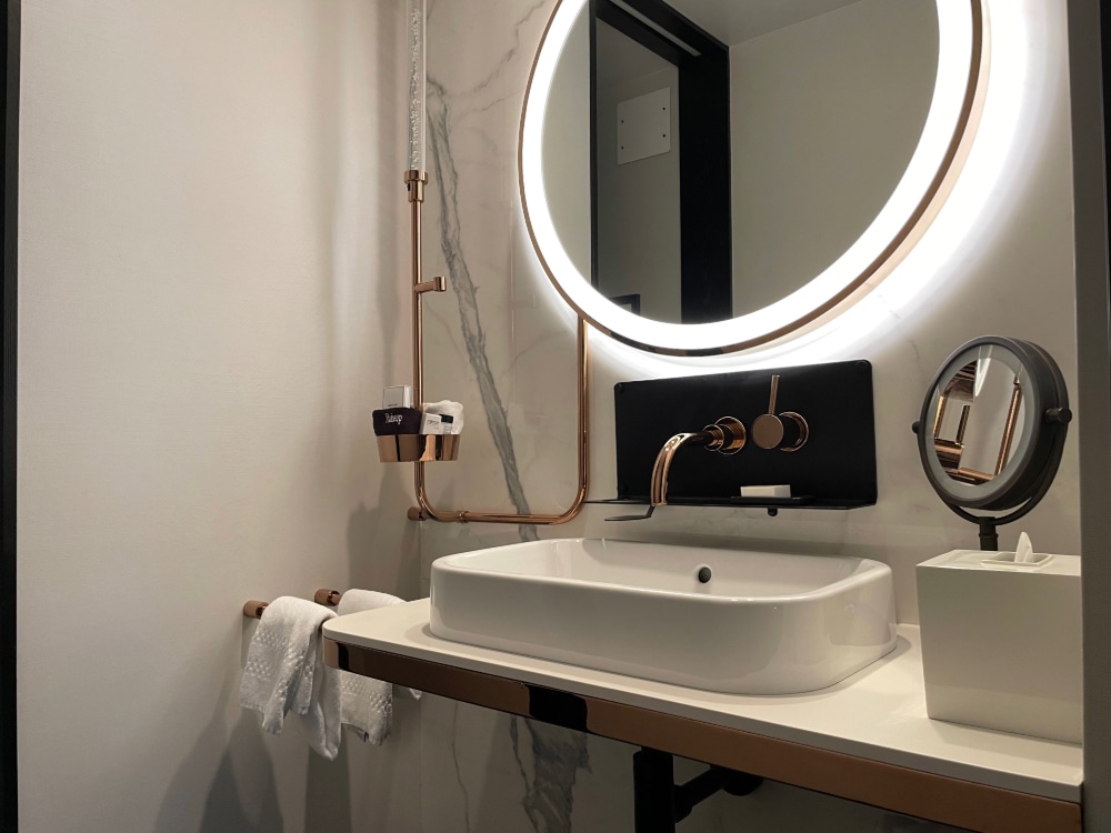 white marble wall and white vanity counter in a hotel master bathroom