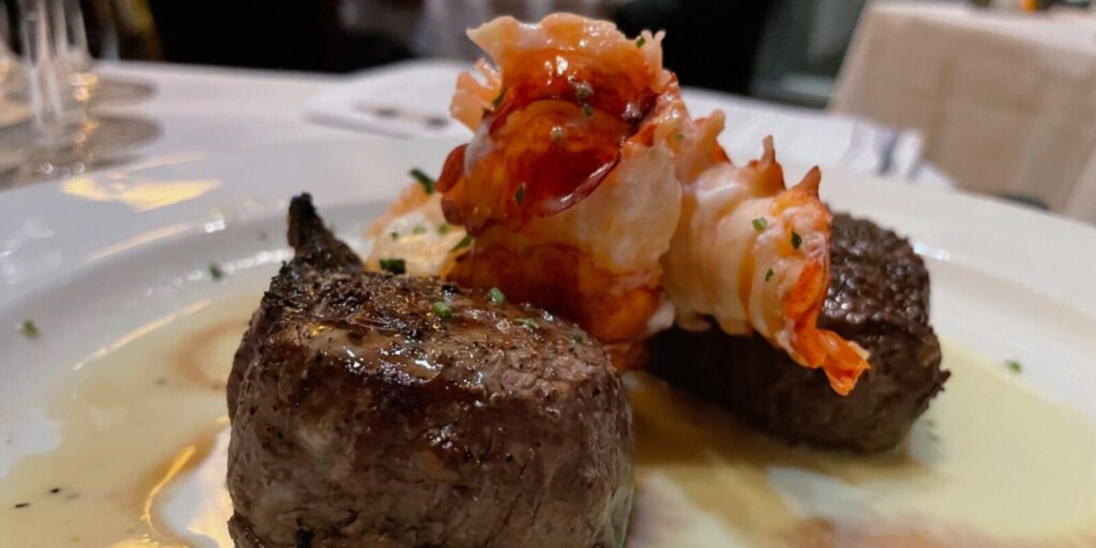 close up view of tenderloin steak topped with poached lobster tail