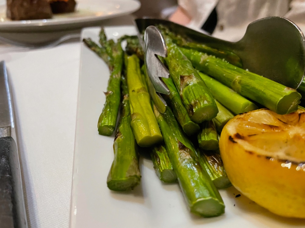 grilled asparagus on a platter with a halved grilled lemon