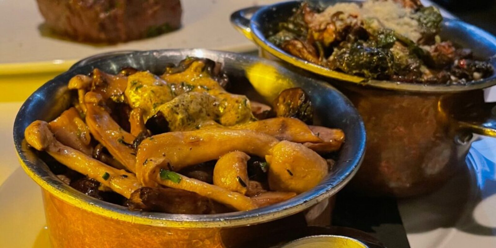 mushroom and brussel sprouts sidedishes in copper pots on a table