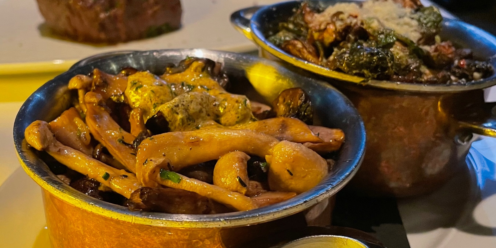 mushroom and brussel sprouts sidedishes in copper pots on a table