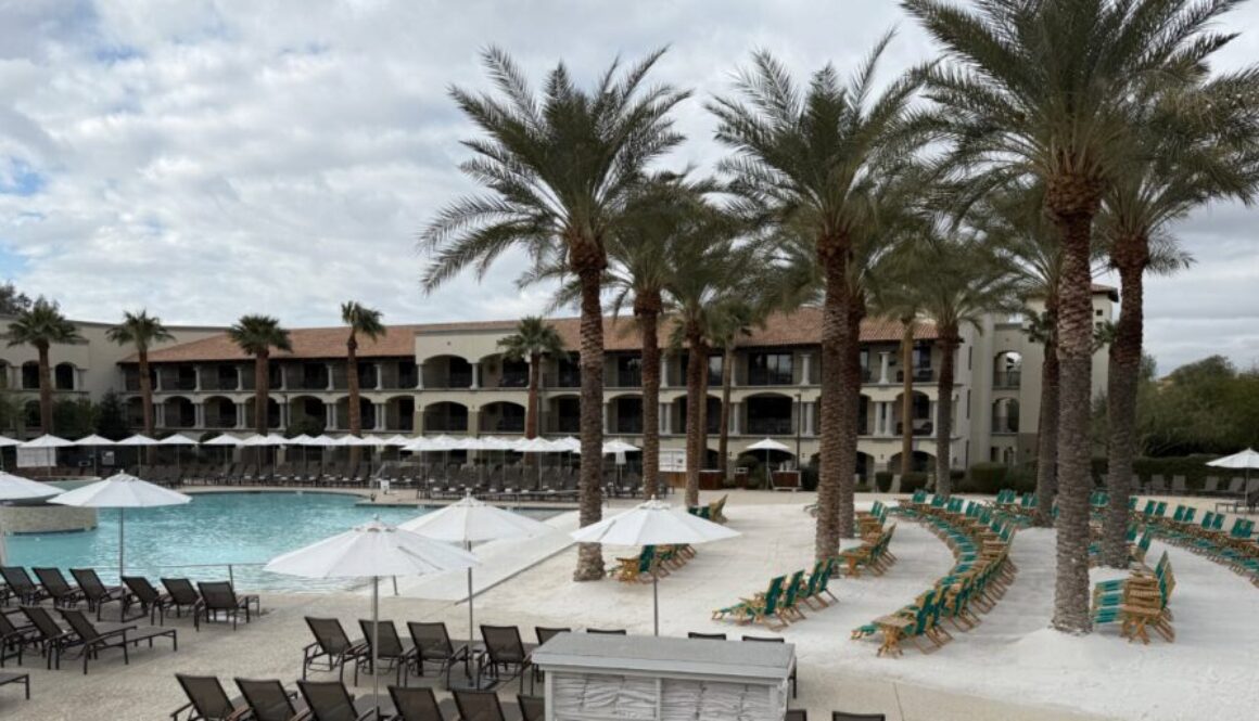 a pool at a resort with a white sand beach and palm trees