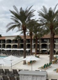 a pool at a resort with a white sand beach and palm trees