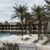 a pool at a resort with a white sand beach and palm trees