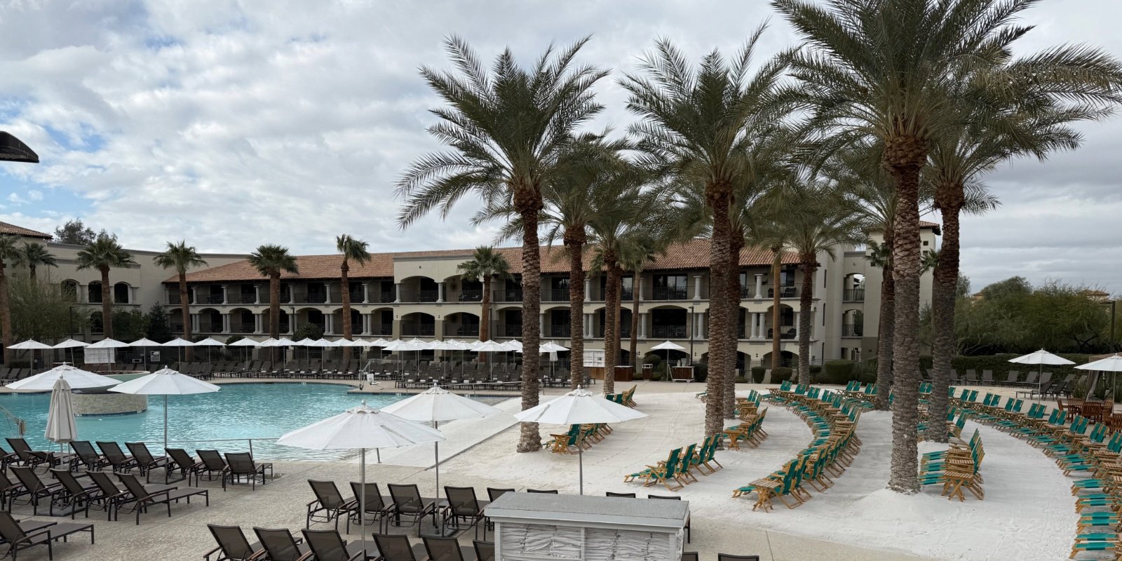 a pool at a resort with a white sand beach and palm trees