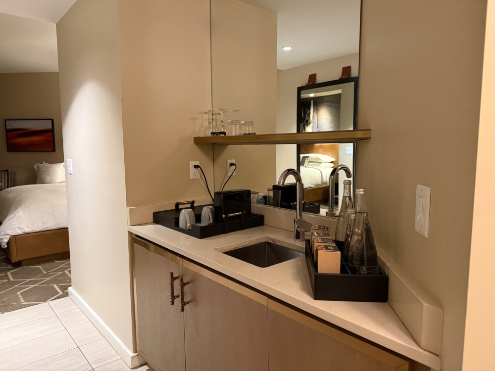 wet bar with sink, coffee maker, cups and bottles of water