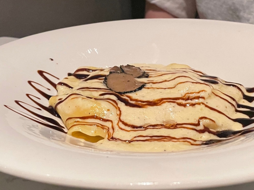 plate of ravioli wth cream sauce and a balsamic drizzle