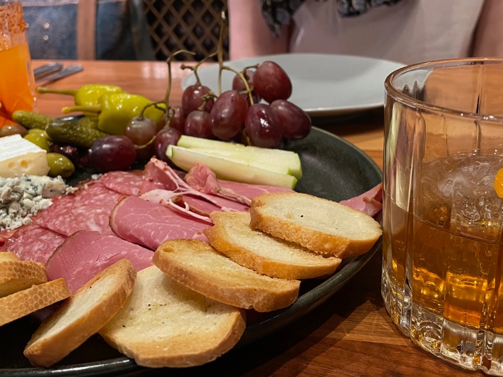 charcuterie platter with crostini, meats, cheeses, grapes and pickled vegetables