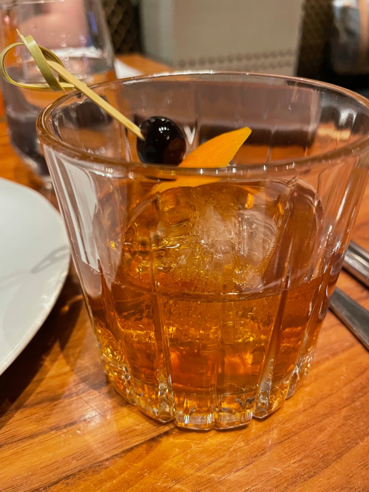 an old-fashioned cocktail with a cherry and orange slice