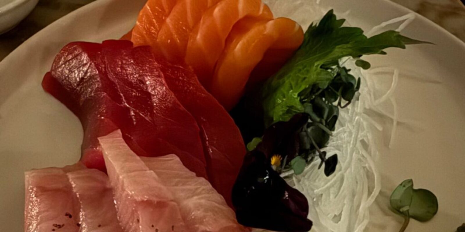 three kinds of sashimi with garnish on a white plate