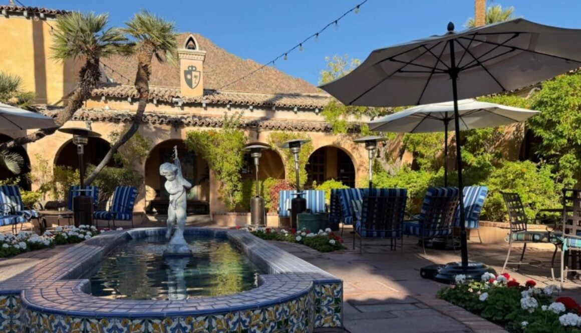 fountain with a stone statue in an outdoor courtyard flanked by several tables