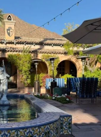 fountain with a stone statue in an outdoor courtyard flanked by several tables