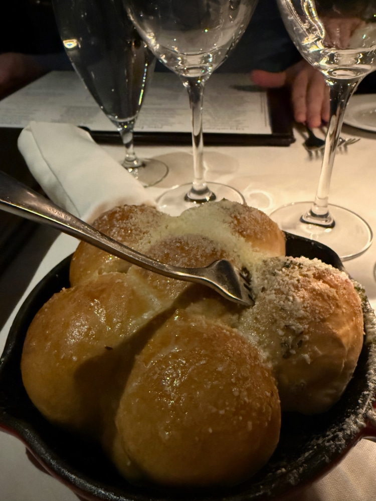 a serving of pull-apart buns in a basket brushed with melted butter and topped with grated cheese